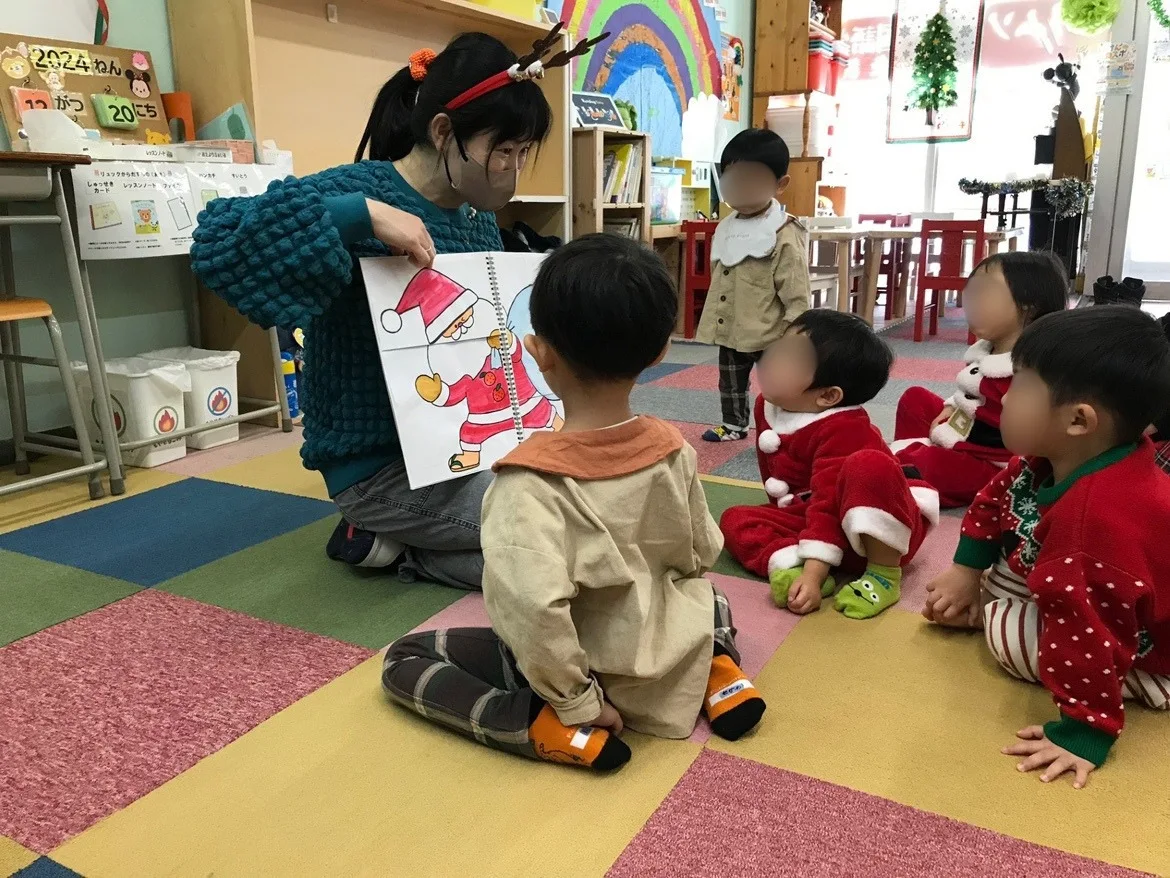 スタッフの絵本を、近くで見つめる子どもたち